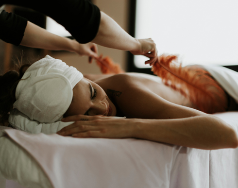 woman receiving a massage with feathers in a spa